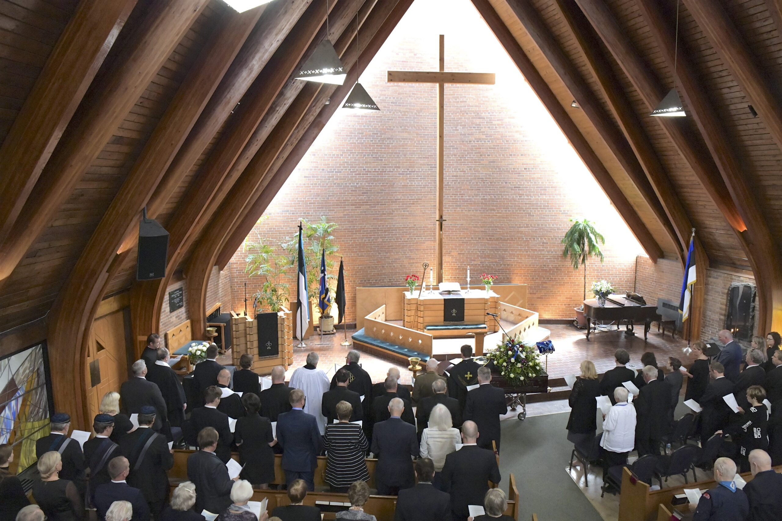 Altari kõrvale olid matusetalituseks asetatud EÜS-i, EELK ja skaudimaleva lipud (vasakul) lisaks soomepoiste lipp, mis on oma alalisel aukohal Peetri kirikus (paremal)